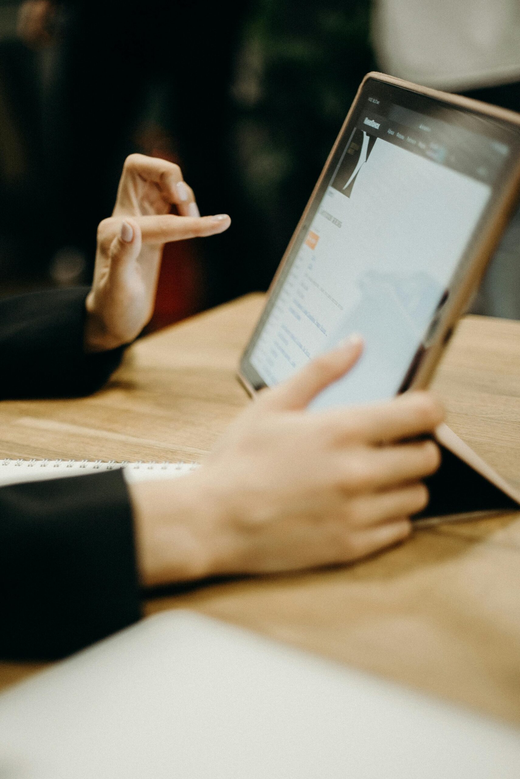 Close-up of hands working on a tablet in a sleek, modern office environment.
