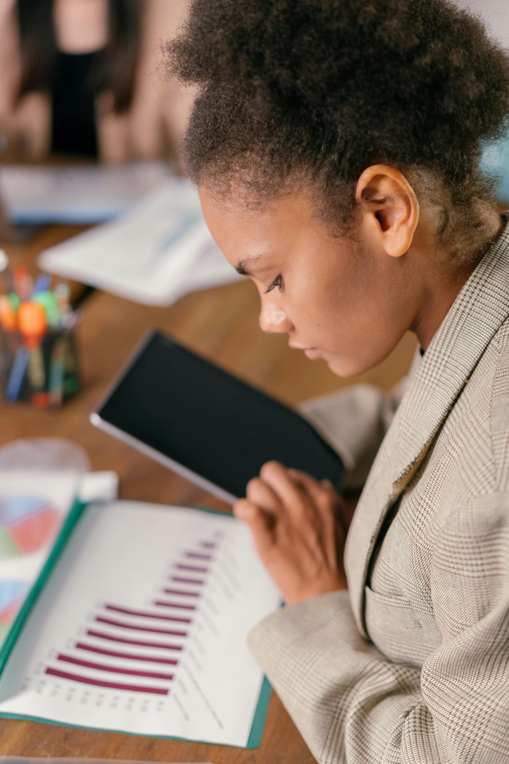 Woman examines chart data on tablet in modern office setting.